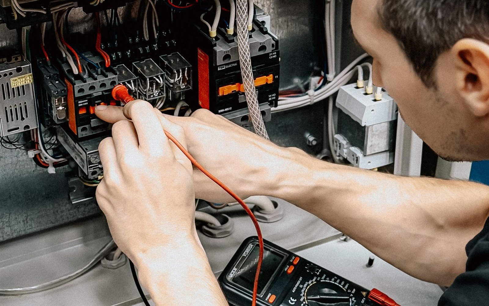 Elektriker misst mit dem Messgerät an einem offenen Schaltschrank