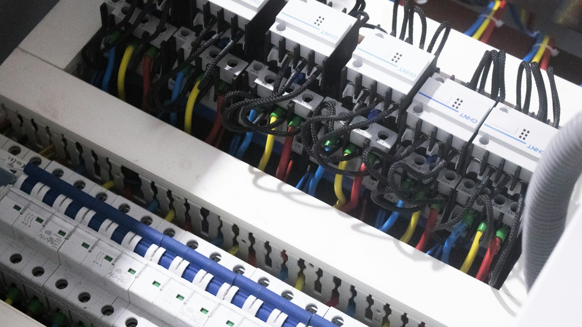 Elektriker prüft mit der Messspitze die Klemmen in einem Verteilerschrank