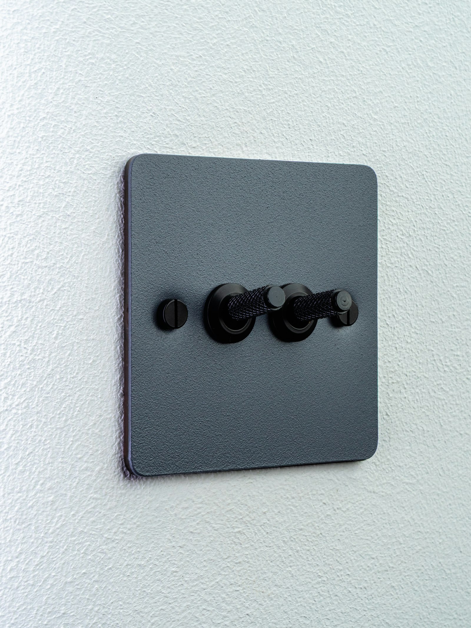 Dunkler Doppelschalter auf einer weißen Wand