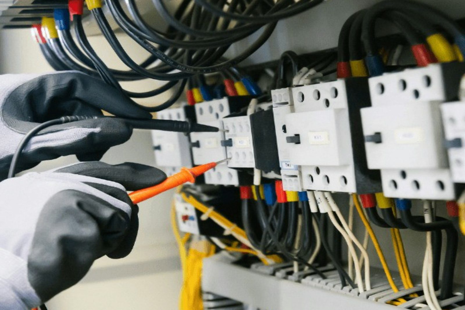 Hände mit Prüfgerät an Schützen in einem Verteiler
